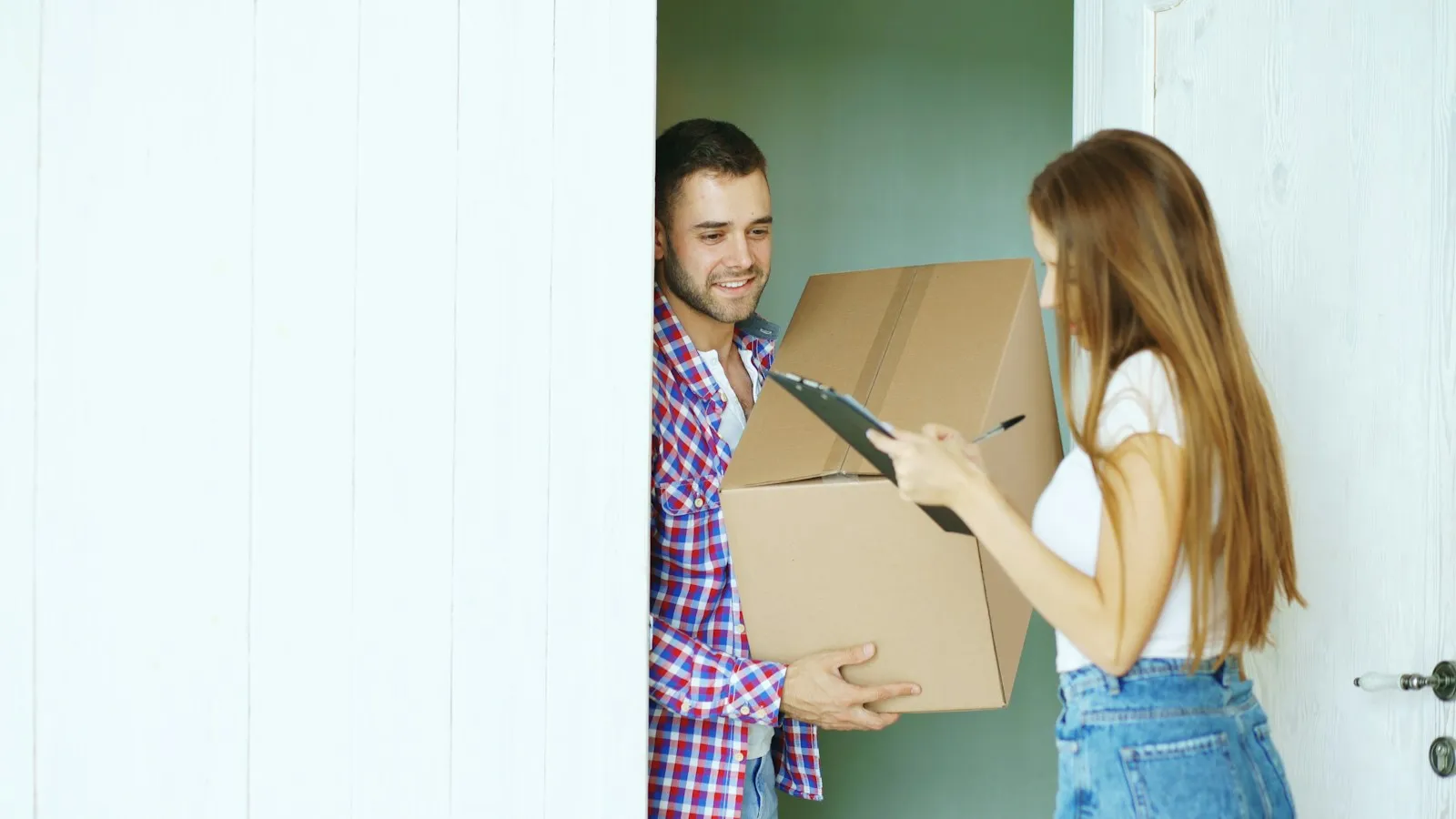 Delivery driver handing a cardboard box to a woman at her door