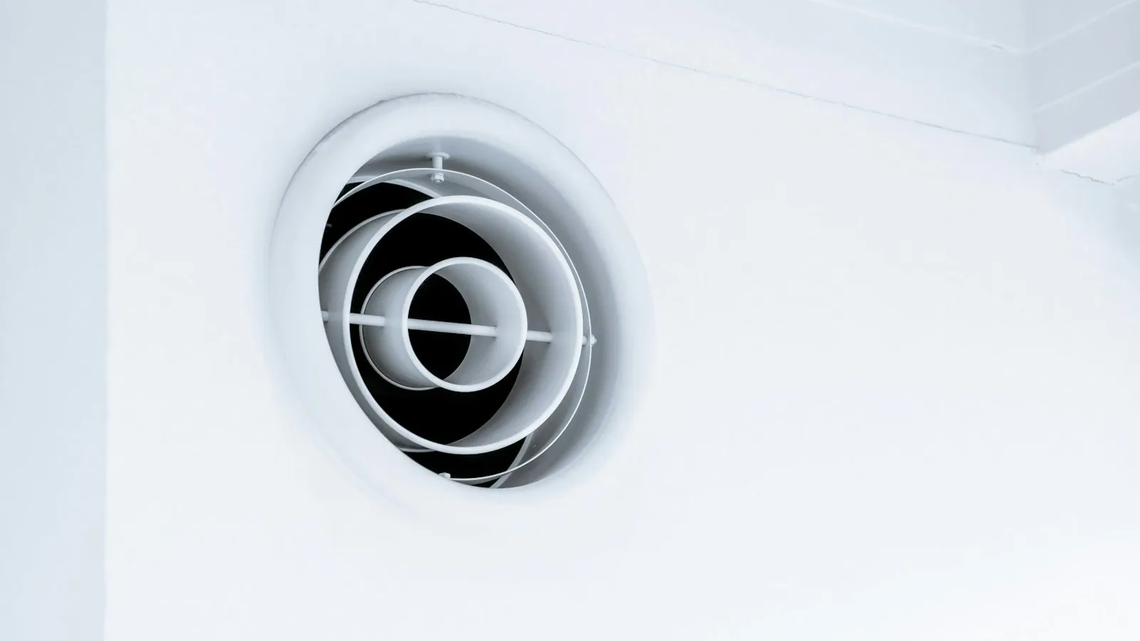Round white exhaust fan vent on a white wall
