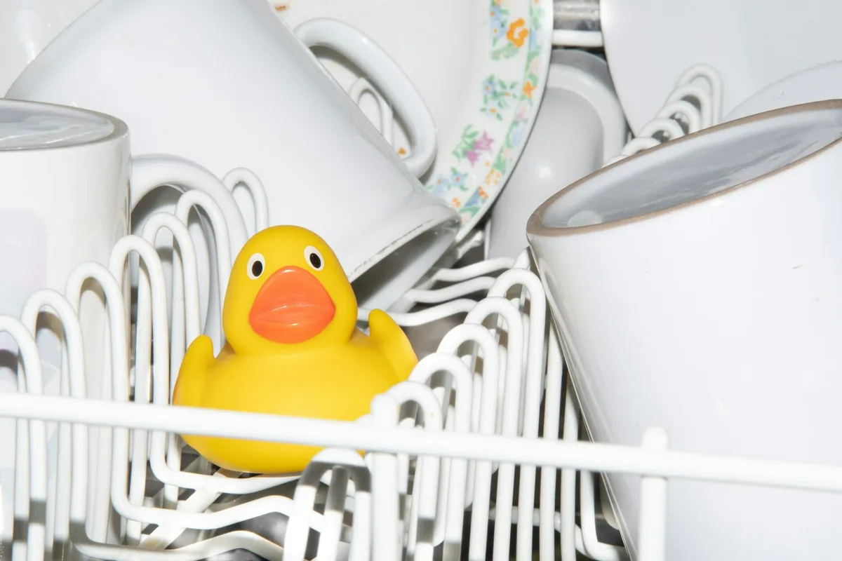A yellow rubber duck sitting in a dishwasher rack