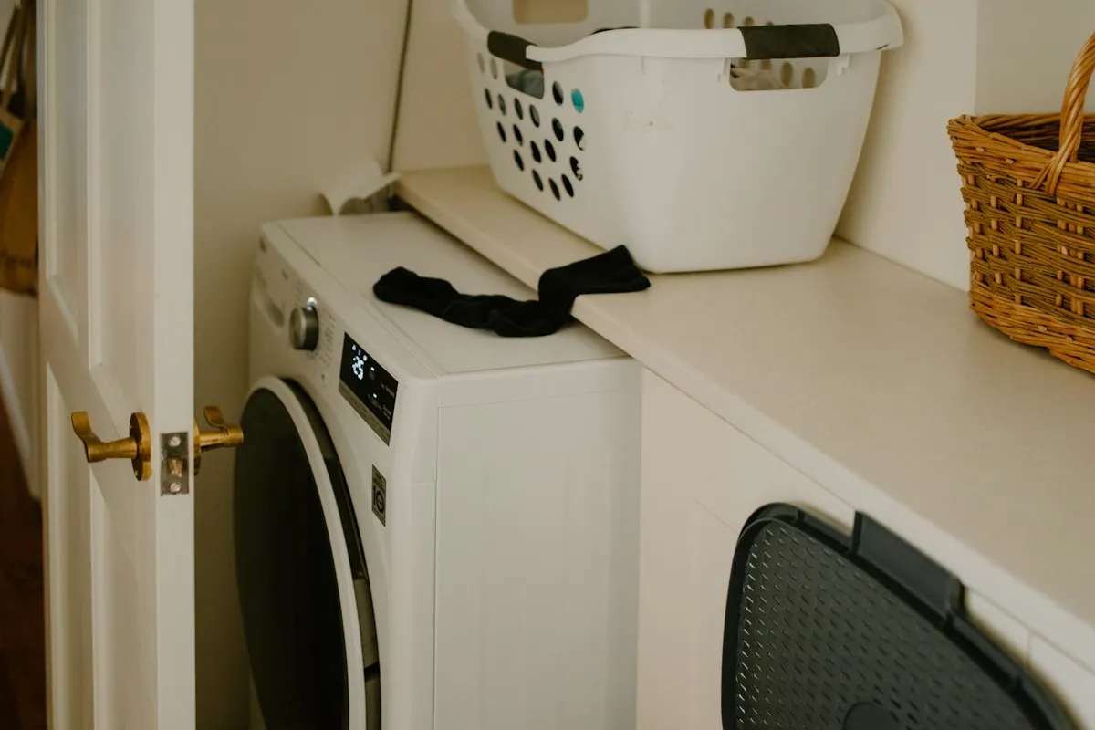 A white washing machine with a laundry basket and a sock