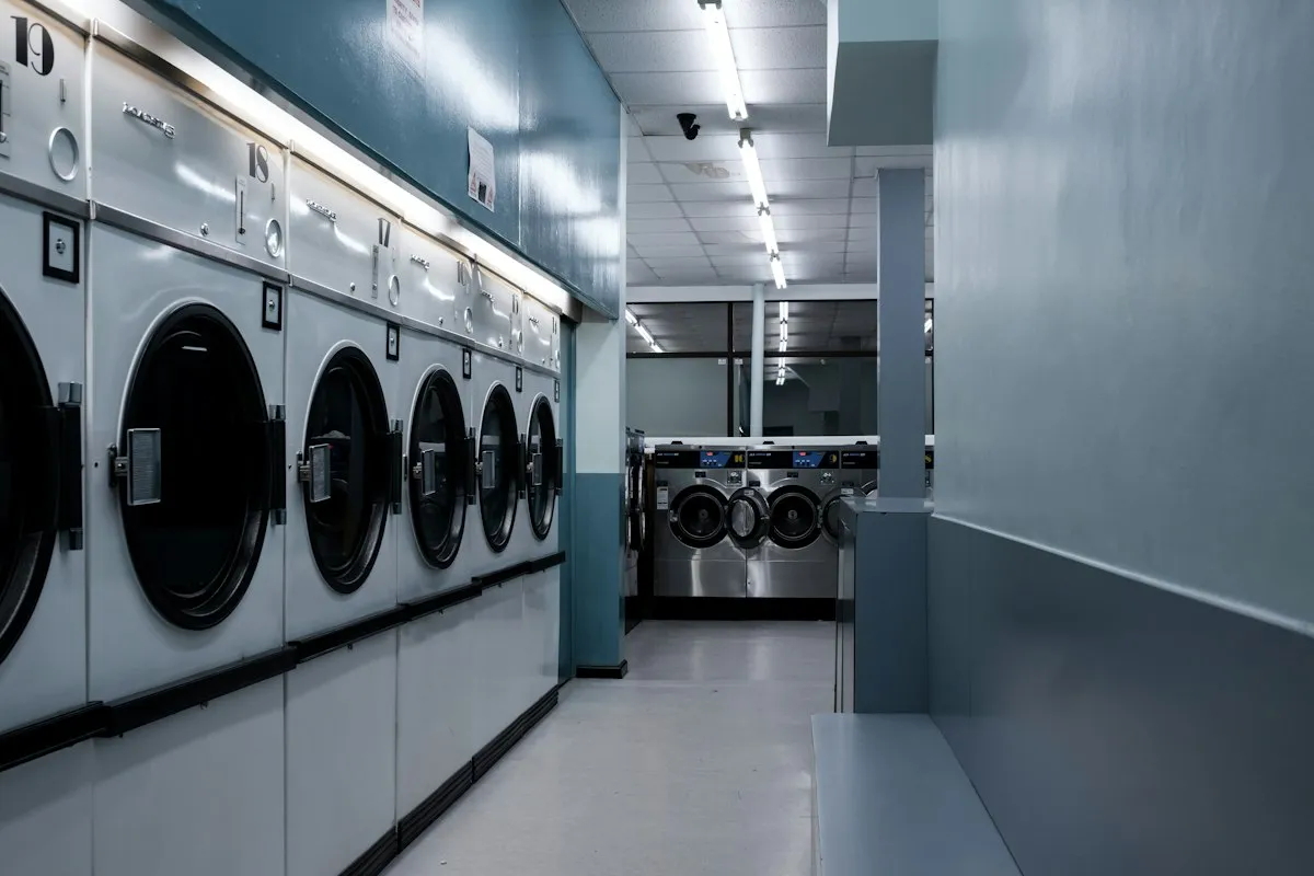 A row of front-loading laundry machines in a laundry room