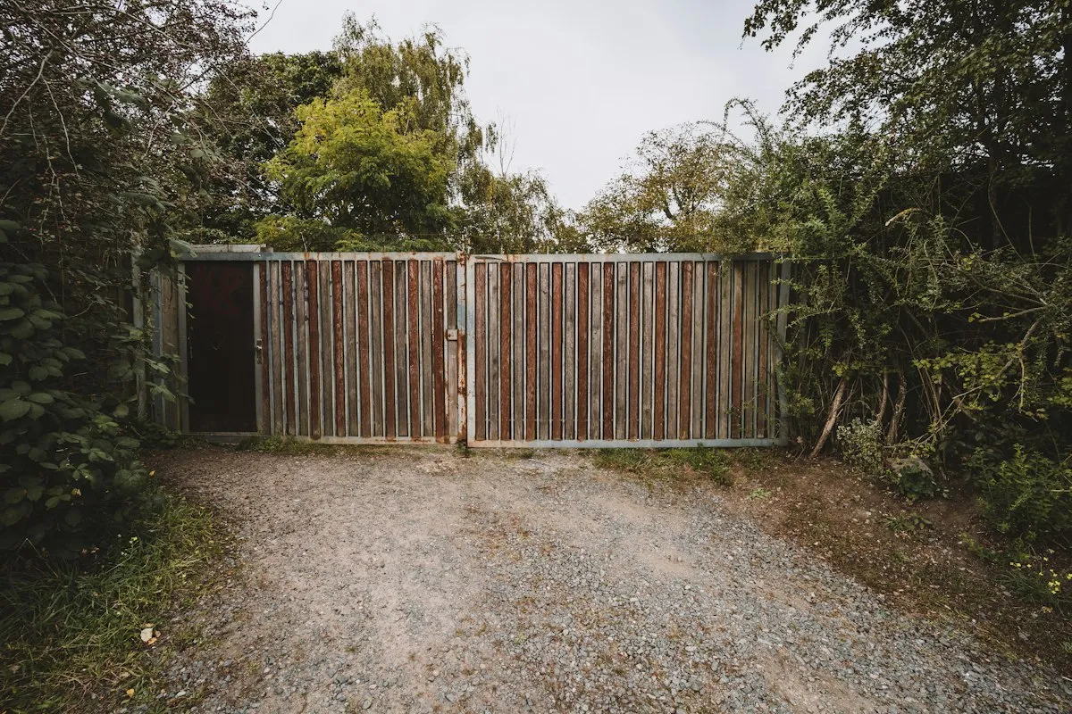 A wooden double gate across a gravel driveway