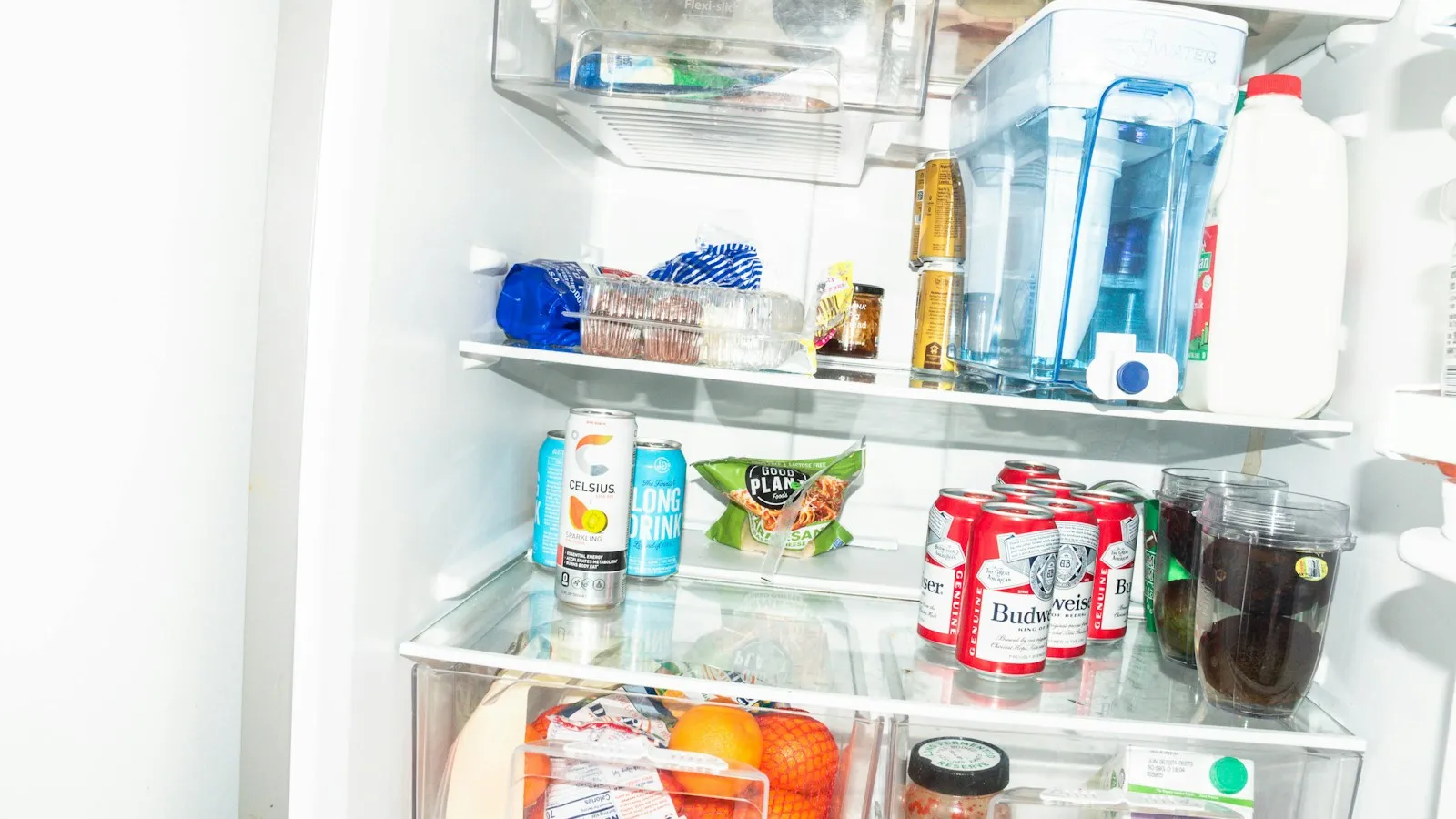 Open refrigerator with drinks and food on the shelves