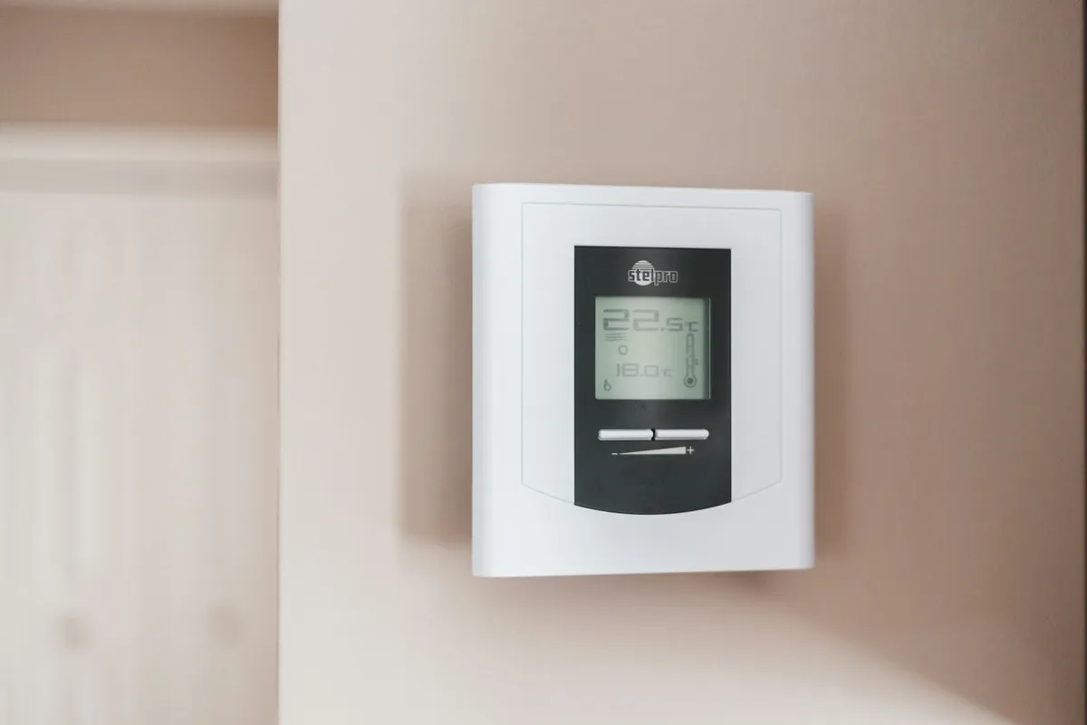 A white digital thermostat on a wall