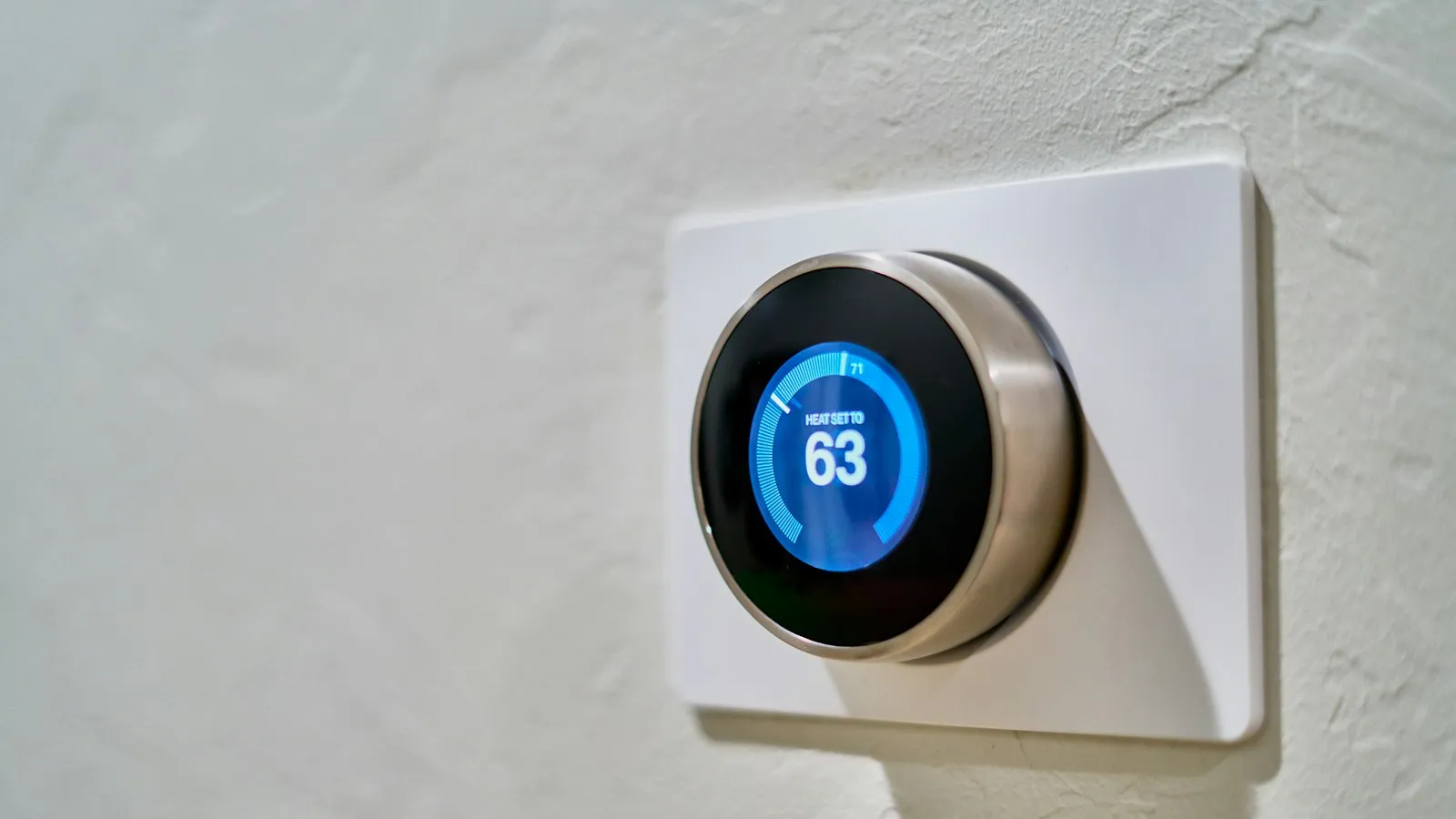 Smart thermostat on a wall showing 63 degrees
