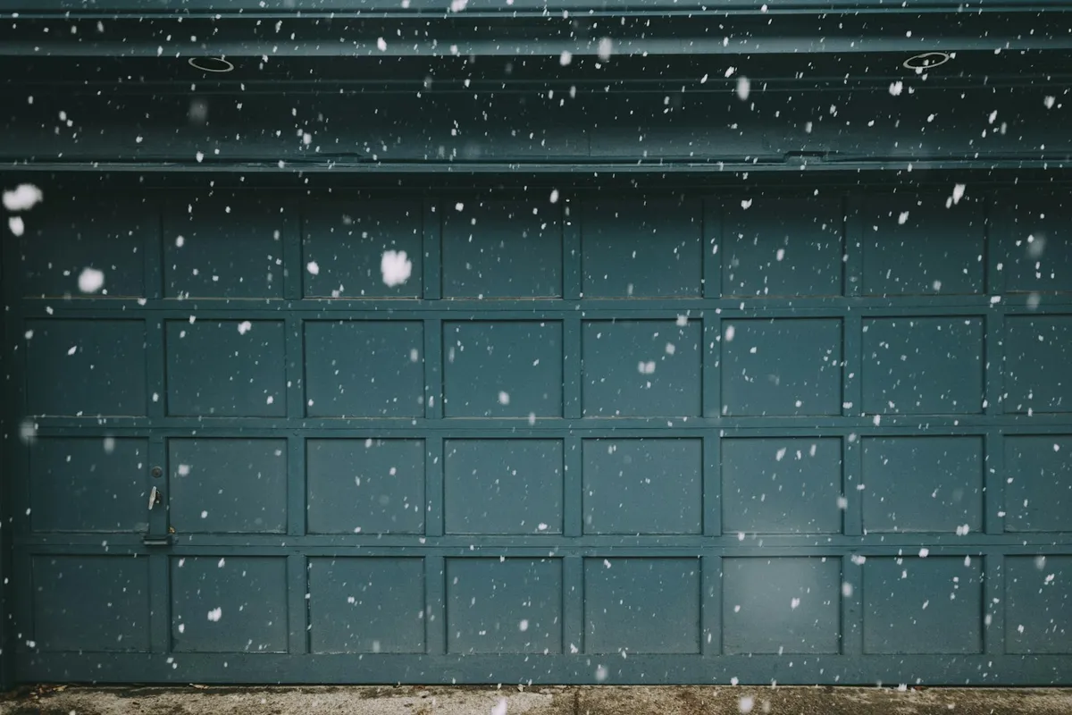 A closed garage door with snow falling