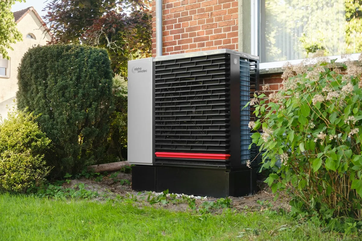 An outdoor heat pump unit next to a brick building