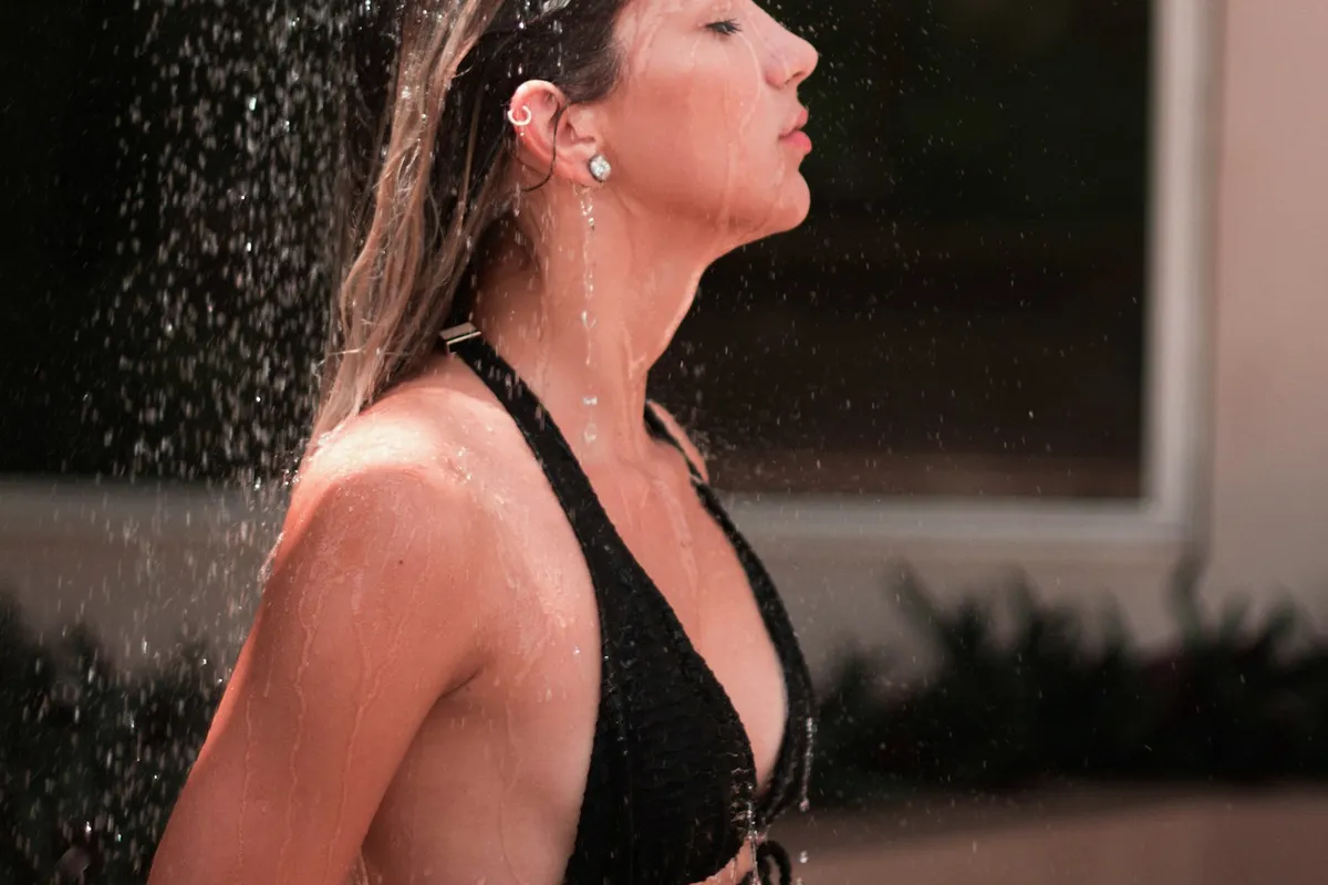 A woman standing under a running shower