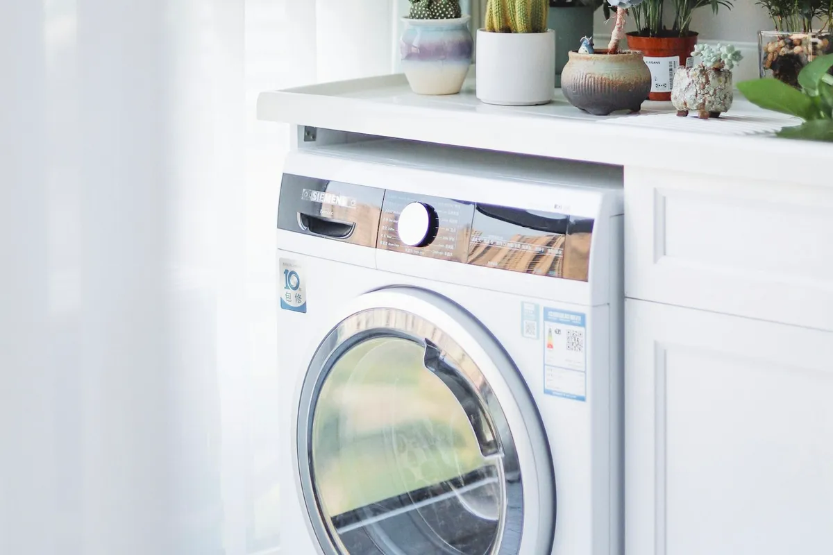 Front-load dryer beside a white cabinet