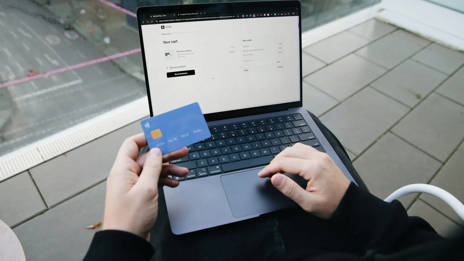 Person holding a bank card while typing on a laptop