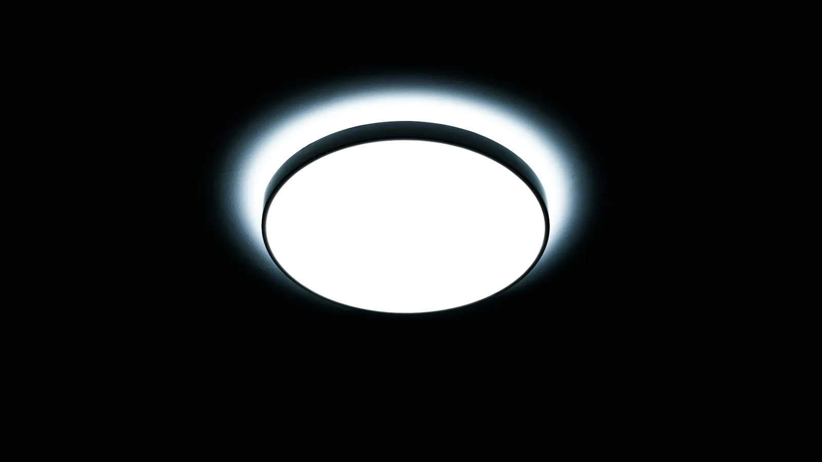 A round white ceiling light fixture glowing against a dark background