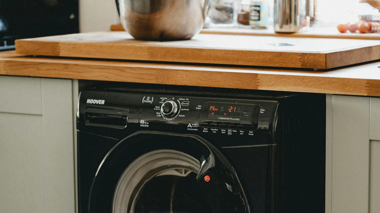 Black front-load washing machine with a laundry basket beside it