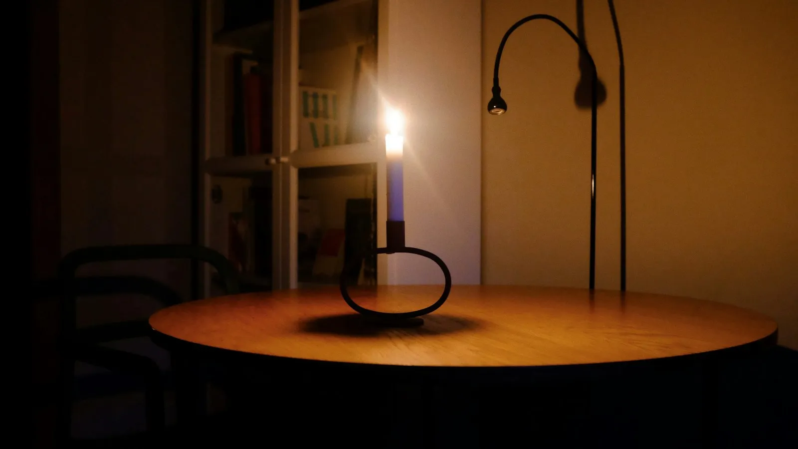 Lit candle on a wooden table in a dark room