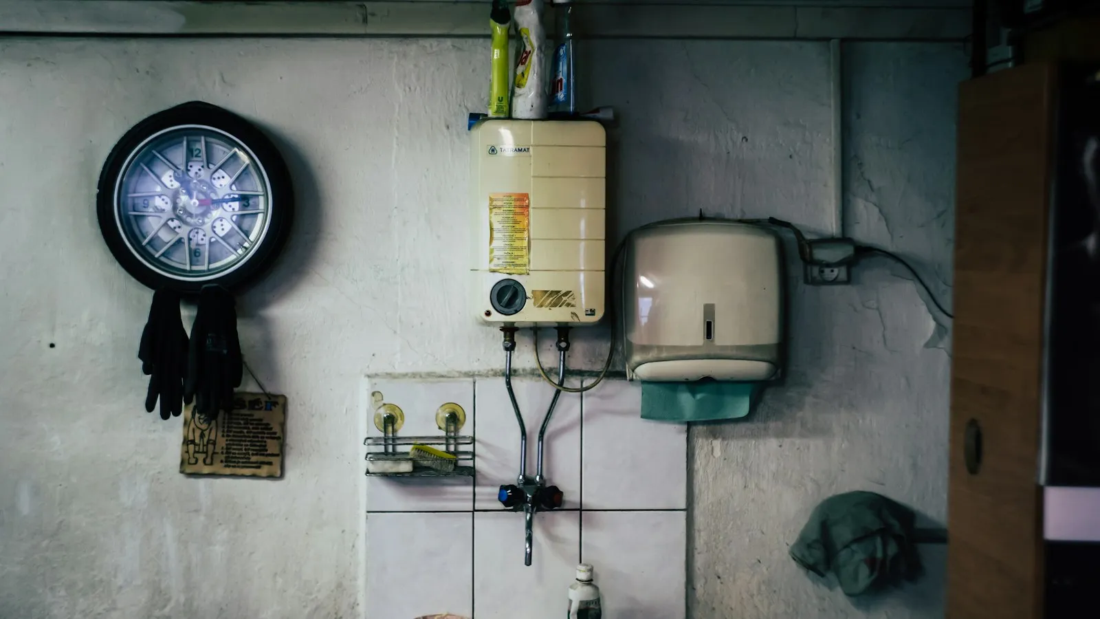Gas water heater and controls mounted on a basement wall with pipes and a gas line