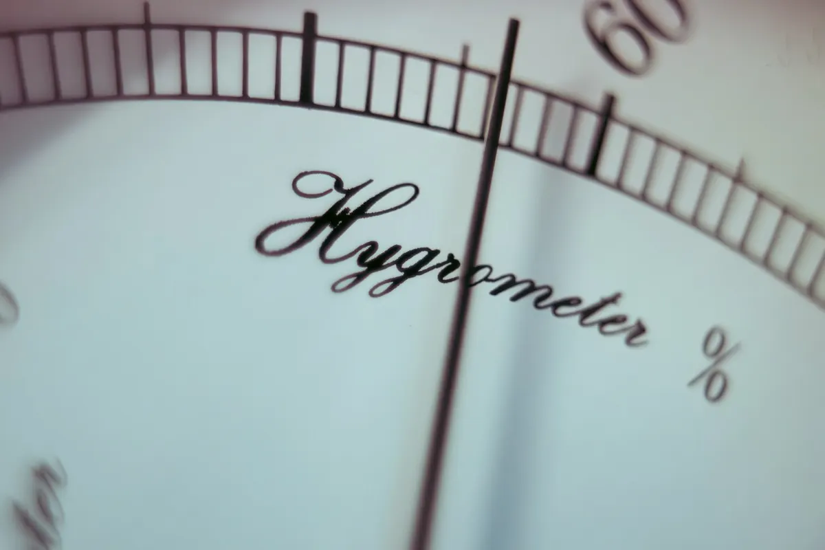 A close-up of a dial hygrometer showing a needle on a percent scale