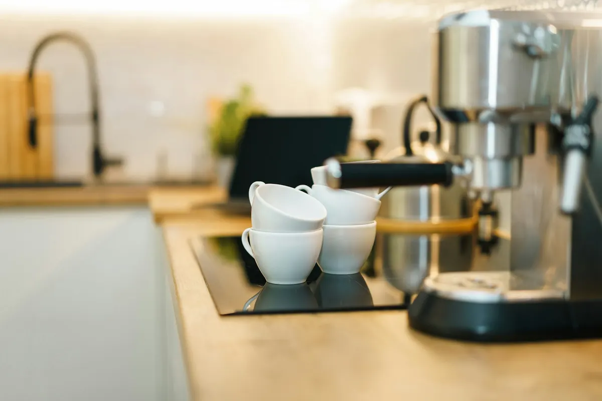 A coffee machine and white cups on a modern kitchen counter