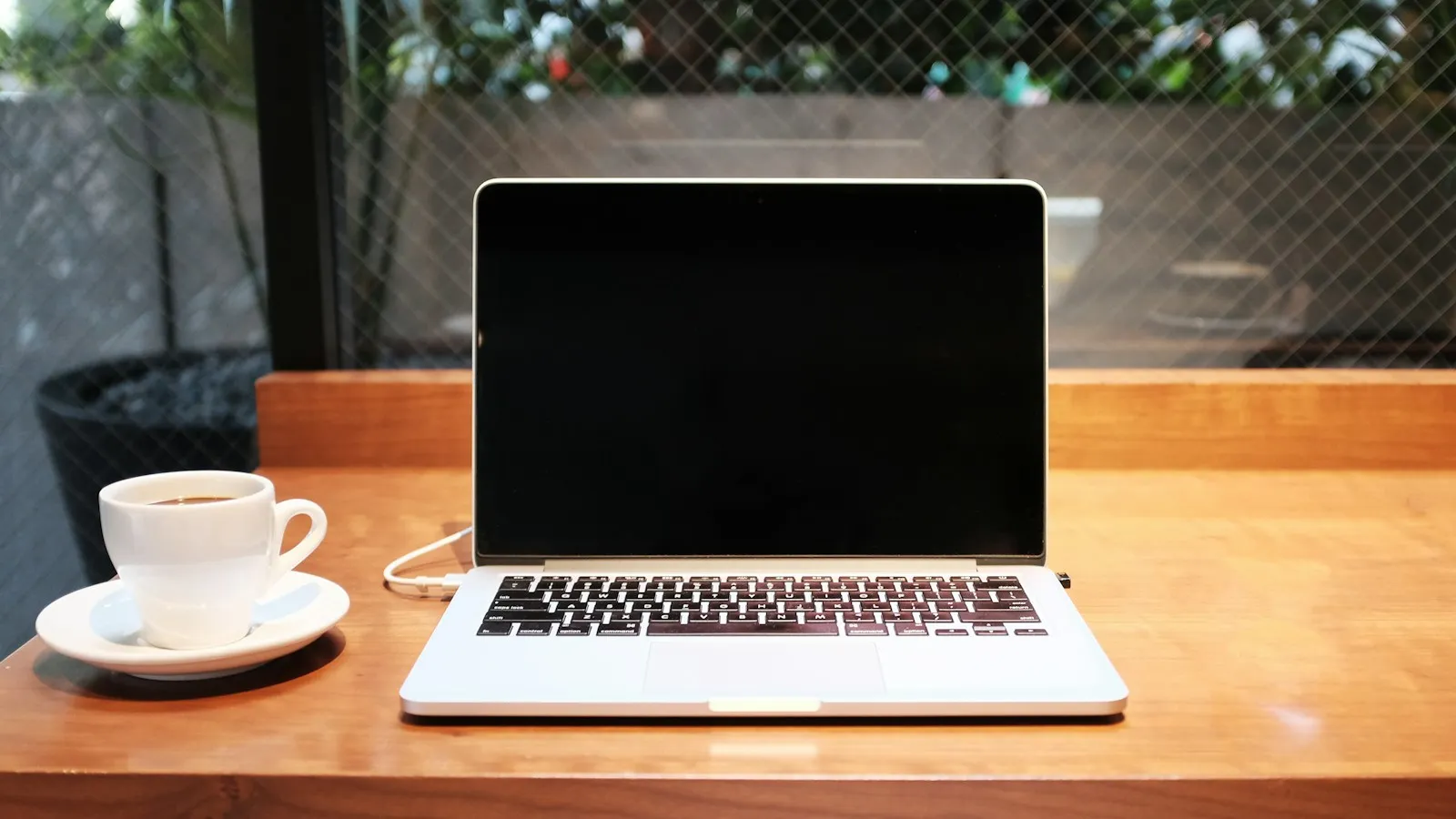 Open laptop on a wooden table next to a cup of coffee