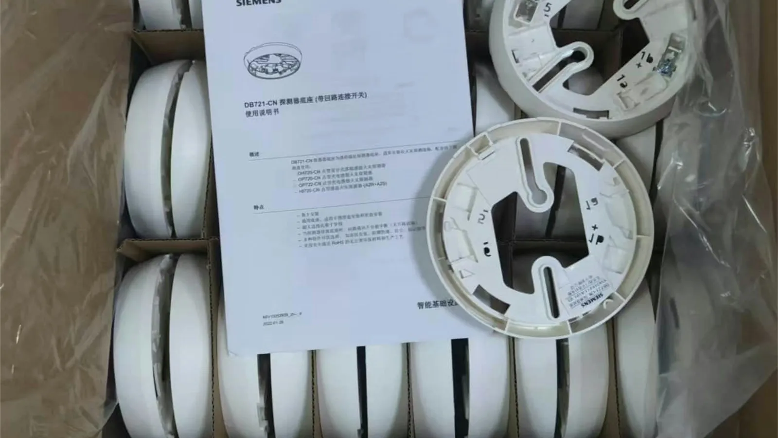 Box of new white smoke detectors with an instruction sheet